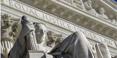 Close-up of a seated statue with a justice inscription.