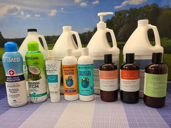 A lineup of various shampoos, conditioners, and skincare products on a table outdoors.