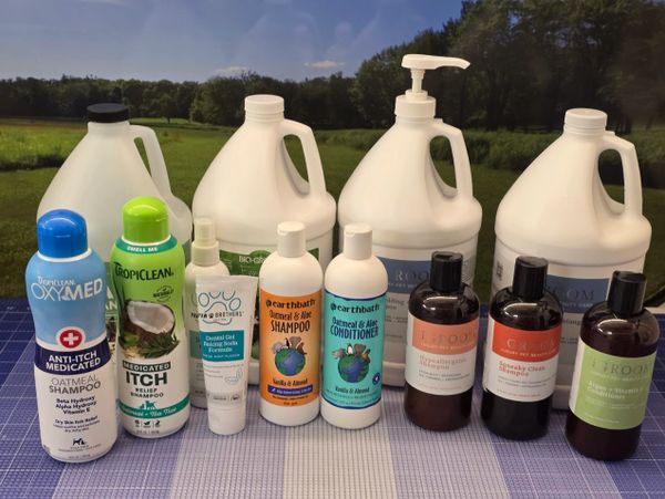 Various pet shampoos and conditioners lined up on a table outdoors.