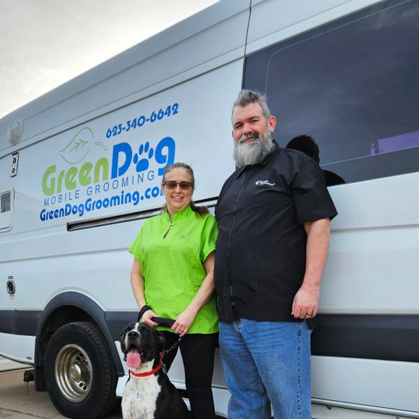 Two groomers and a dog pose in front of a Green Dog Mobile Grooming van.