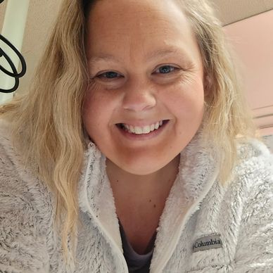 Smiling woman with blonde hair in a cozy fleece jacket indoors.