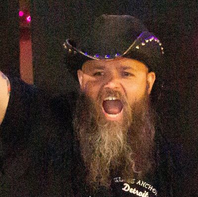Bearded man in a black hat shouting or cheering.