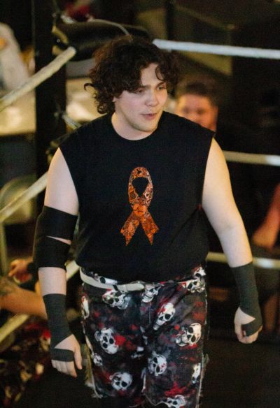 Wrestler in skull pants and black sleeveless shirt.