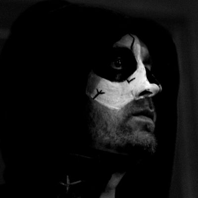 Person with face paint resembling a skull in a dark setting.