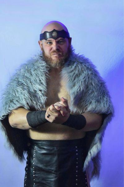 Man in warrior costume with fur cloak and headband.