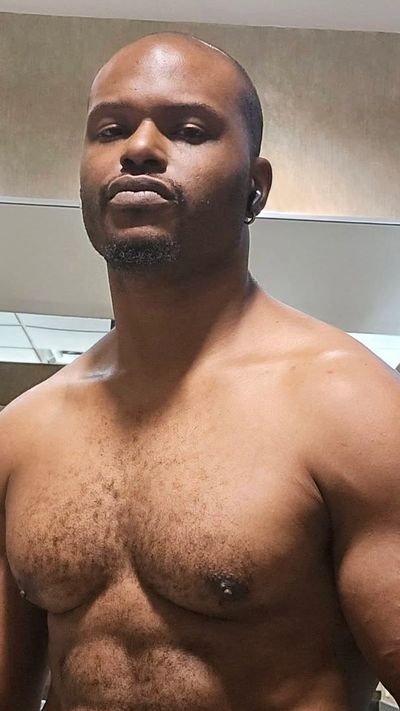 Shirtless man posing confidently indoors.