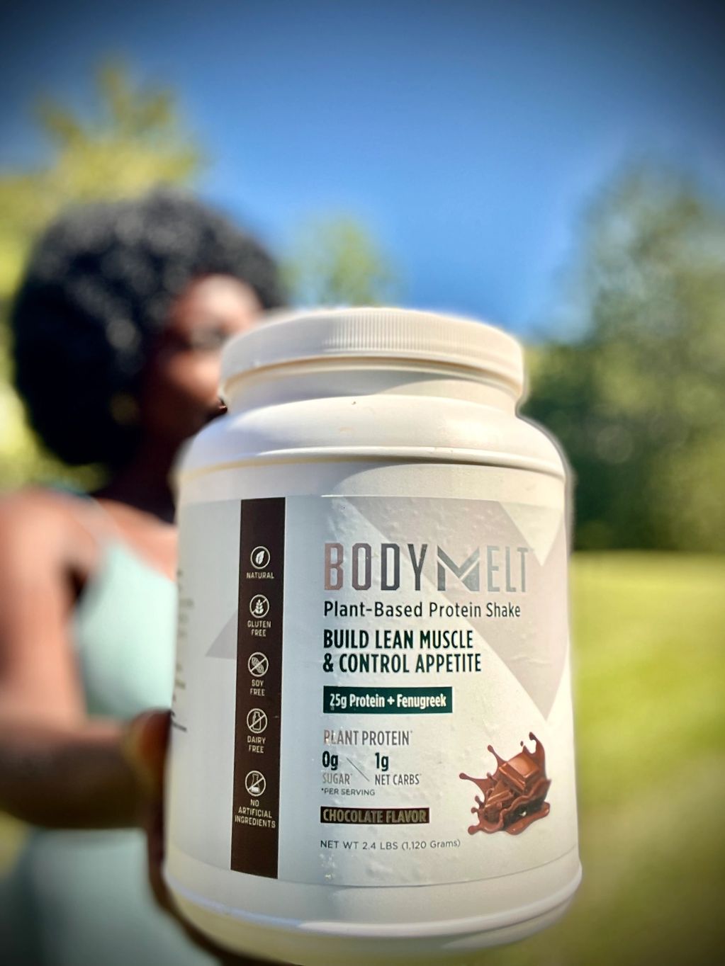 A black woman holding Body Melt protein shake.