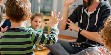 Children and an adult engage in a high-five activity indoors.