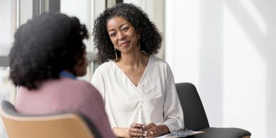 Two women engaged in a thoughtful conversation in a bright room.