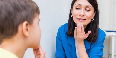 A woman in blue teaching a child to speak.