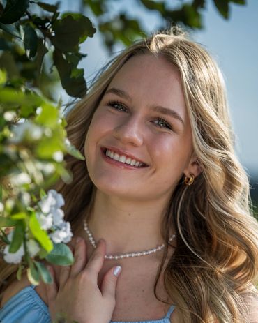 Blonde girl standing by leaves on a tree
