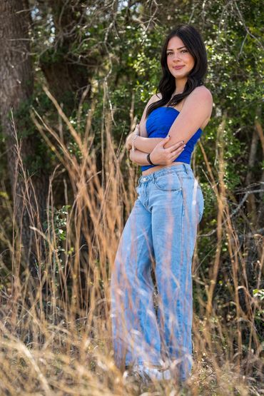 Girl crossed arms standing in tall grass.