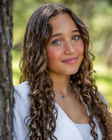 Girl with long curly hair leaning against tree