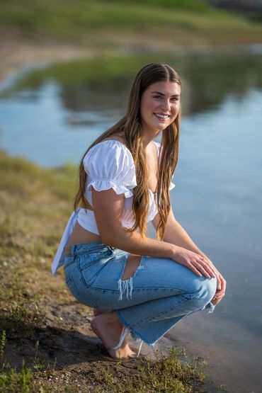 Girl squatting by lake