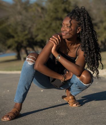 Girl squatting with leg out looking off in distance