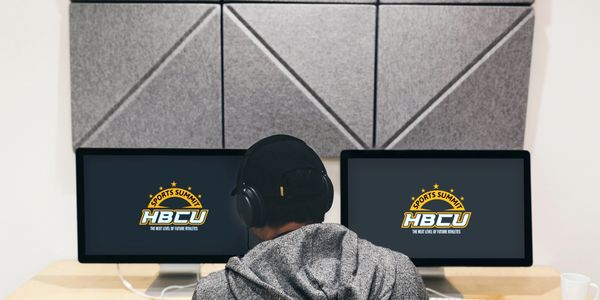 Person wearing headphones working on dual monitors displaying HBCU Sports Summit logos.