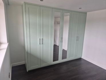 A modern wardrobe with mirrored doors in a minimalistic room.