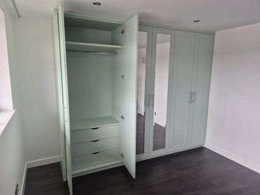 Modern empty wardrobe with open doors and mirrored panels in a minimalist room.