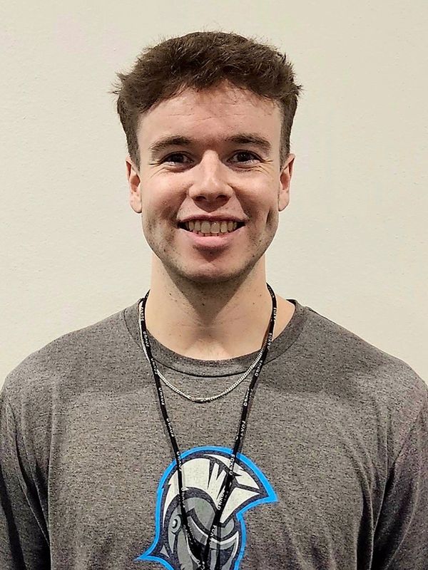 Smiling young man wearing a gray t-shirt with a Spartan helmet logo.