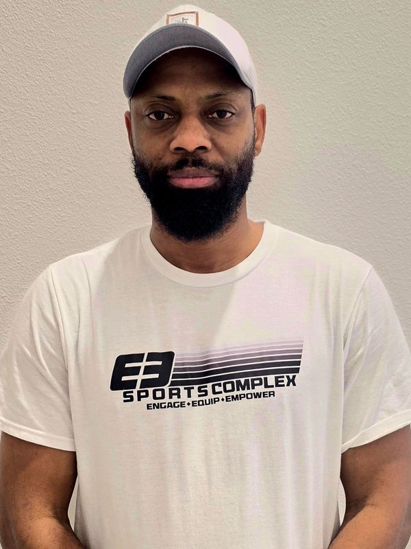 Man with beard wearing a white cap and E3 Sports Complex t-shirt.