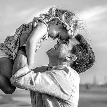 Father joyfully lifting his daughter, sharing a loving moment.