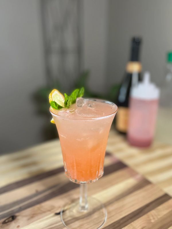 Lemonade with strawberry purée with vodka and topped with Prosecco garnished with lemon and mint.
