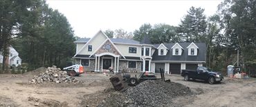 House under construction with gravel and construction equipment.