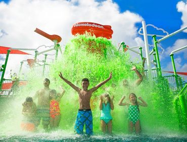 Kids and adults enjoy a green slime splash at a Nickelodeon water park.