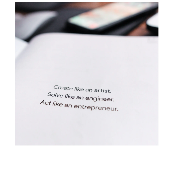 Open blank book with text:"Create like an artist. Solve like an engineer. Act like an entrepreneur."