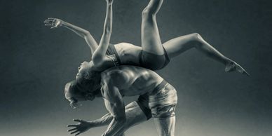 2 dancers, 1 balancing on the back of the other (A woman flipping over a man, back to back.)