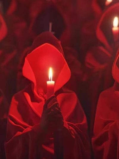 Red cloaked figures holding candles.