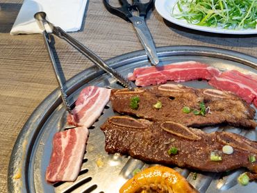 Grilled meat, shrimp, and vegetables on a Korean BBQ grill.