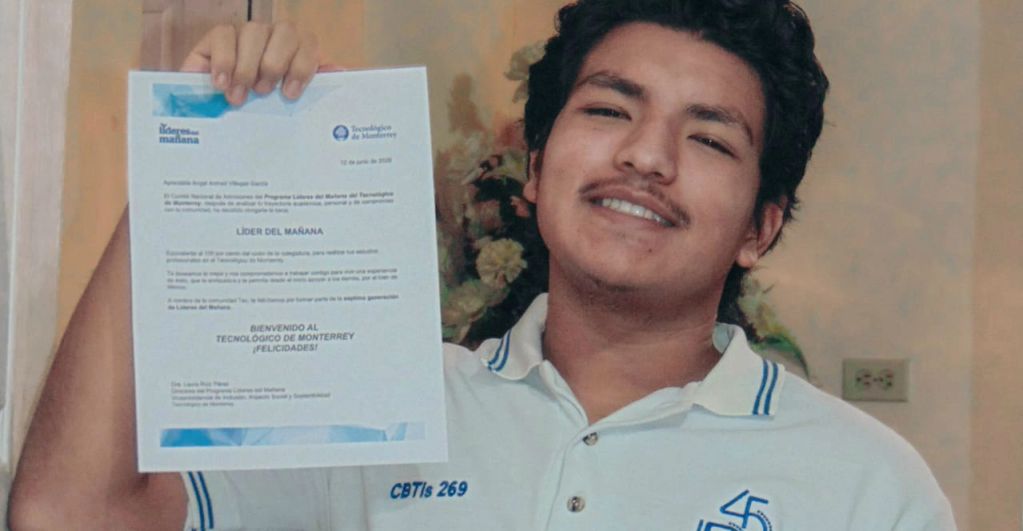 Young man holding an acceptance letter from Tecnológico de Monterrey, smiling proudly.
