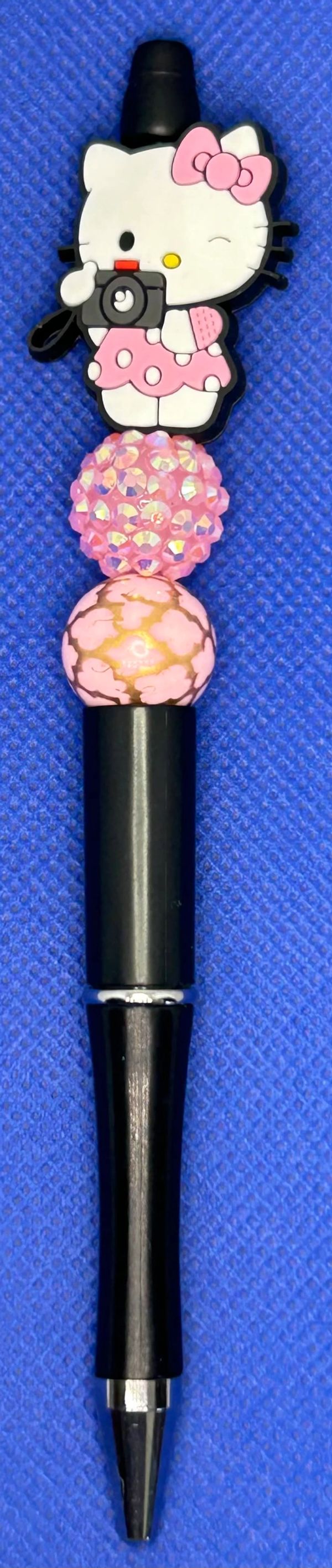 Hello Kitty-themed pen with pink beads on a blue background.
