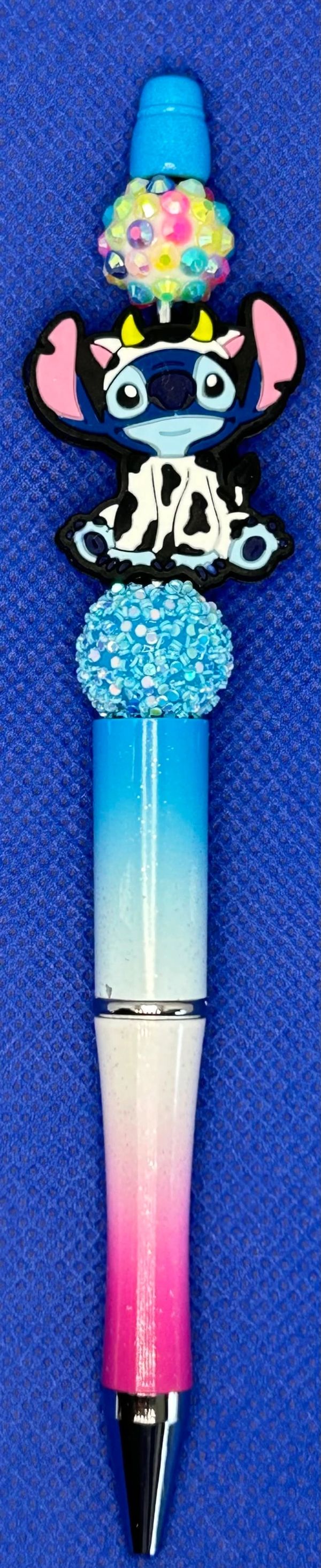 Decorative pen featuring a Stitch cow charm and colorful beads.