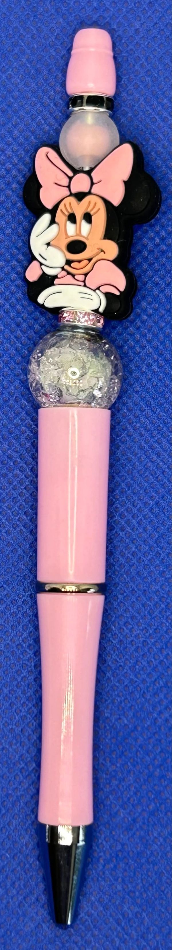 Pink pen with Minnie Mouse topper on a blue textured background.