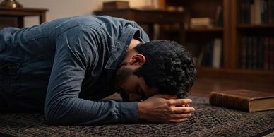 A man in deep prayer or reflection, lying on the floor with hands clasped.