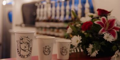 Three Nutmeg Palace cups on horse trailer ledge with flowers and syrups. 