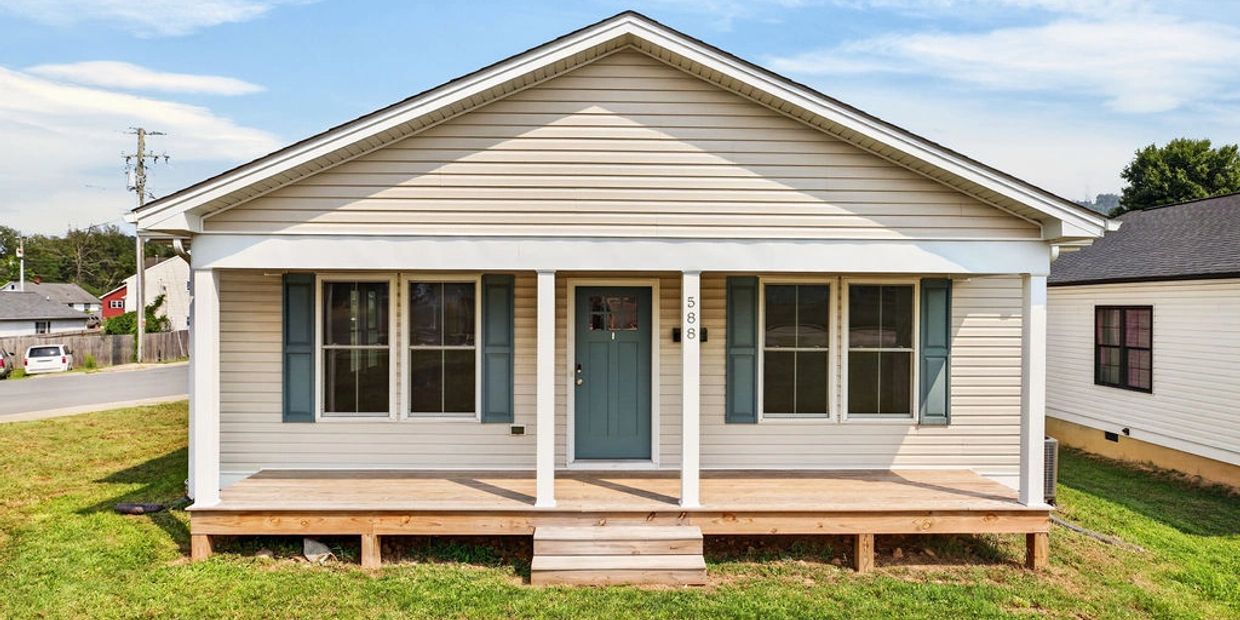 Small beige house with blue door and porch.