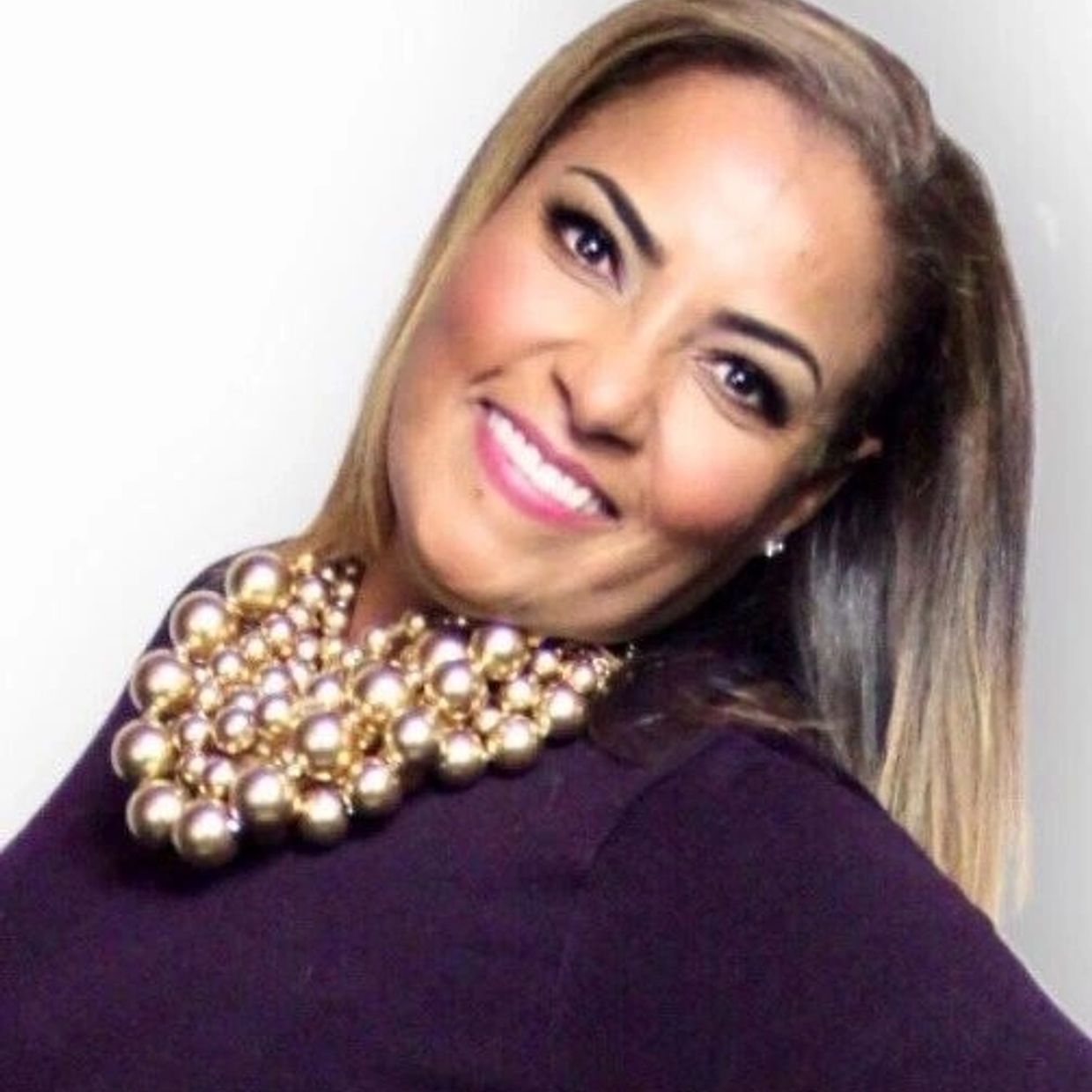 Smiling woman with a statement pearl necklace and blonde hair.