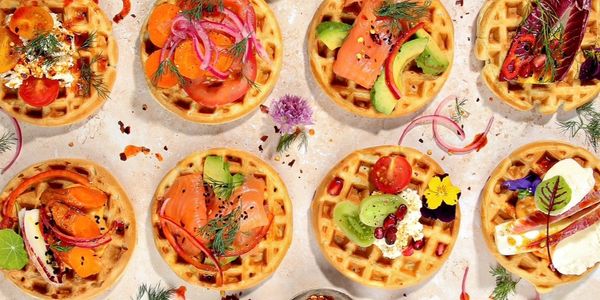 Assorted savory waffles topped with fresh vegetables, smoked salmon, and herbs.