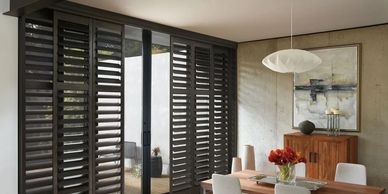 Wood shutters for tall window doors in a dark stain in dining room. Anytime wood shutters collection