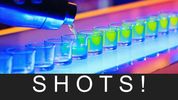 Colorful shots lined up on a bar counter under vibrant lights.