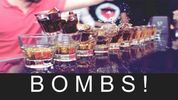 A row of colorful layered shots called bombs on a bar counter.