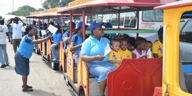 Children and adults riding a colorful train at an outdoor event.