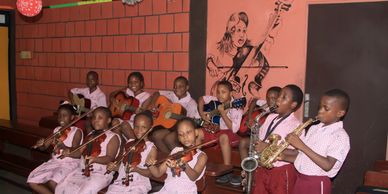 Young children playing various musical instruments in a classroom.