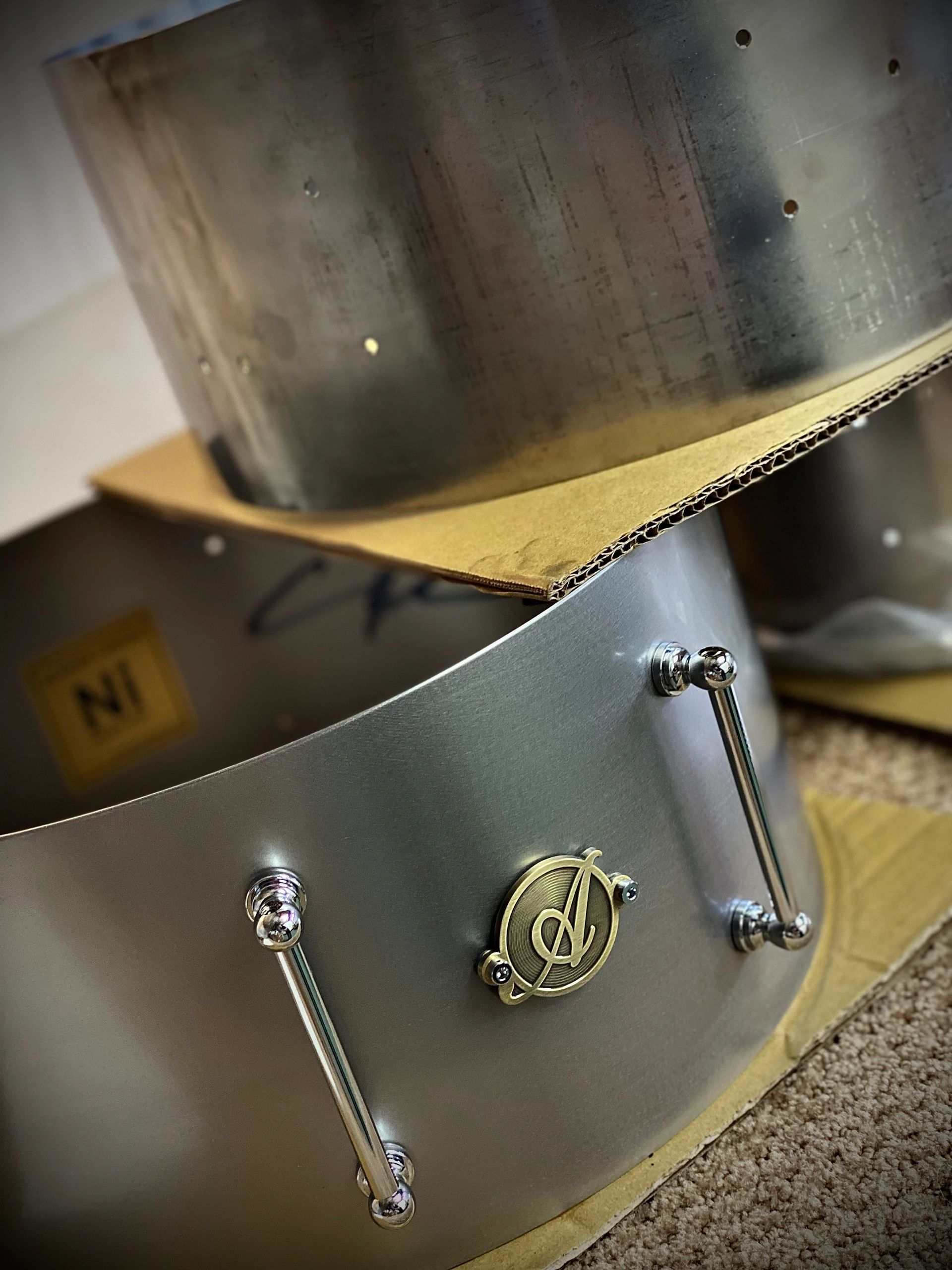 Close-up of a metal drum with a logo and tension rods.