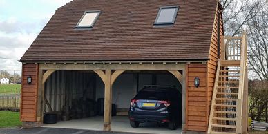 An oak framed double bay garage with an external staircase to office space above.