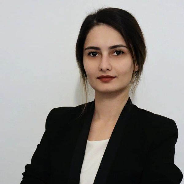 Confident woman in a black blazer with a neutral expression.