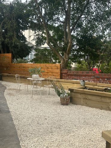 Outdoor seating area with gravel, small chairs, and plants.